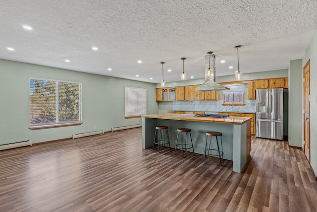 kitchen with a baseboard heating unit, pendant lighting, island range hood, a breakfast bar, and appliances with stainless steel finishes