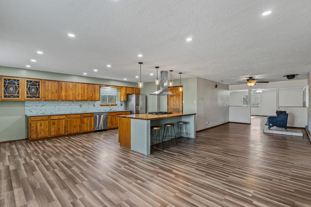 kitchen with a wood stove, hanging light fixtures, ceiling fan, decorative backsplash, and appliances with stainless steel finishes