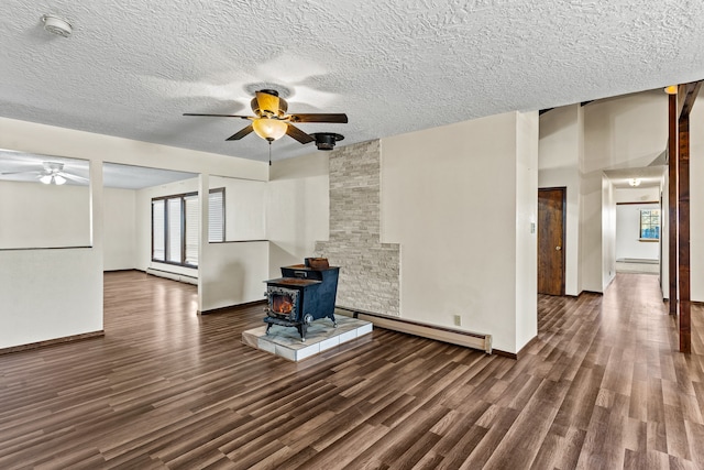 unfurnished living room with baseboard heating, a wood stove, and dark hardwood / wood-style floors