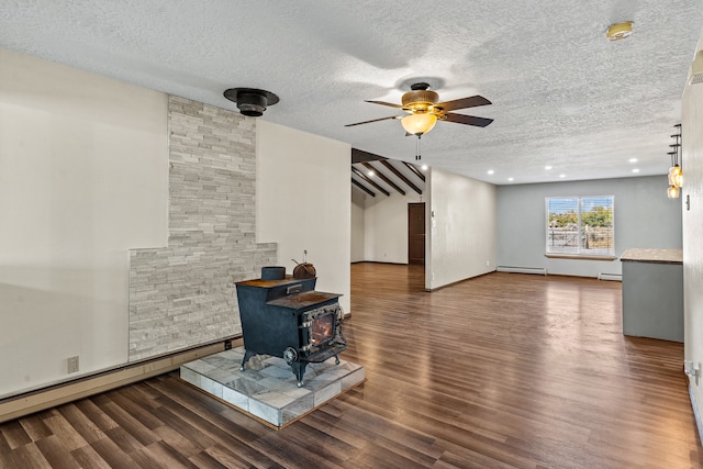 living room featuring a textured ceiling, dark hardwood / wood-style flooring, a wood stove, and baseboard heating