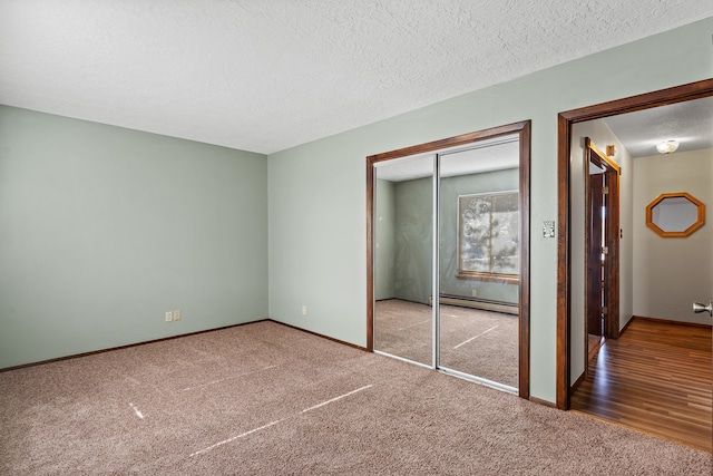 unfurnished bedroom with carpet flooring, a closet, a baseboard radiator, and a textured ceiling