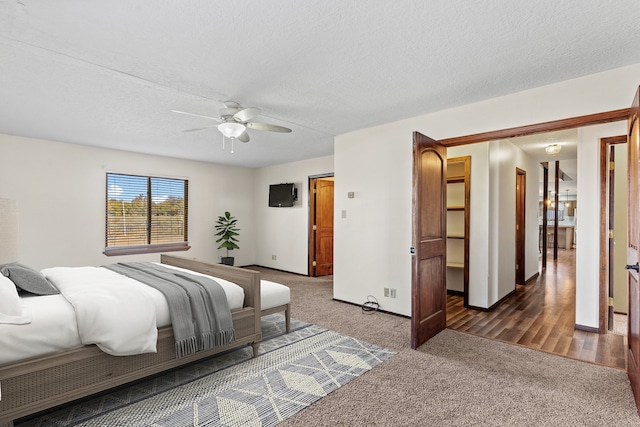 bedroom featuring ceiling fan, a textured ceiling, and dark colored carpet