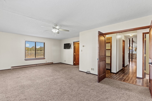 spare room with ceiling fan, dark carpet, a textured ceiling, and a baseboard heating unit