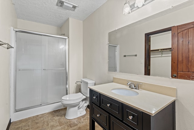 bathroom featuring vanity, toilet, a textured ceiling, and walk in shower