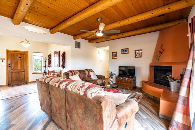 living room with beam ceiling, wood ceiling, light hardwood / wood-style flooring, ceiling fan, and a fireplace