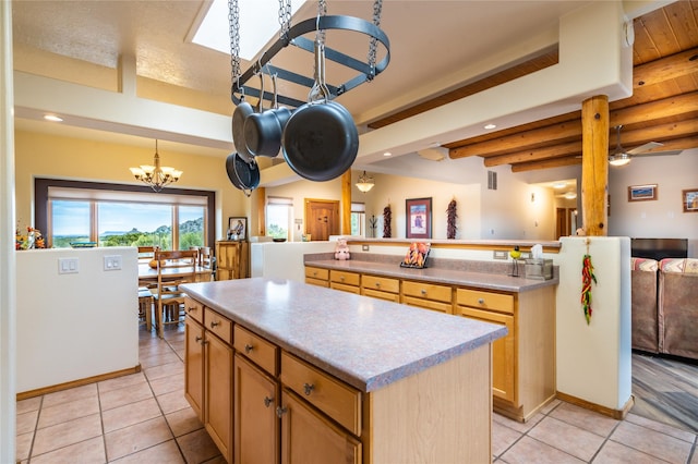 kitchen featuring beamed ceiling, a center island, hanging light fixtures, and light tile patterned floors