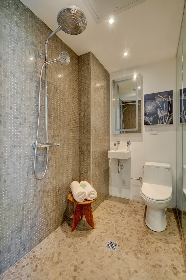 bathroom with a tile shower, tile patterned flooring, sink, and toilet