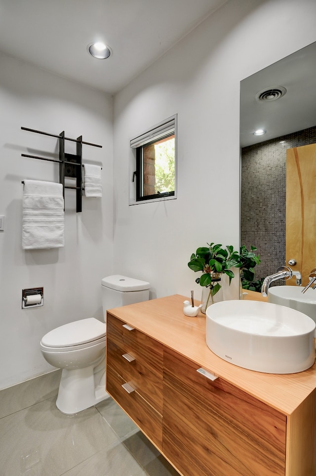 bathroom with toilet, vanity, and tile patterned flooring