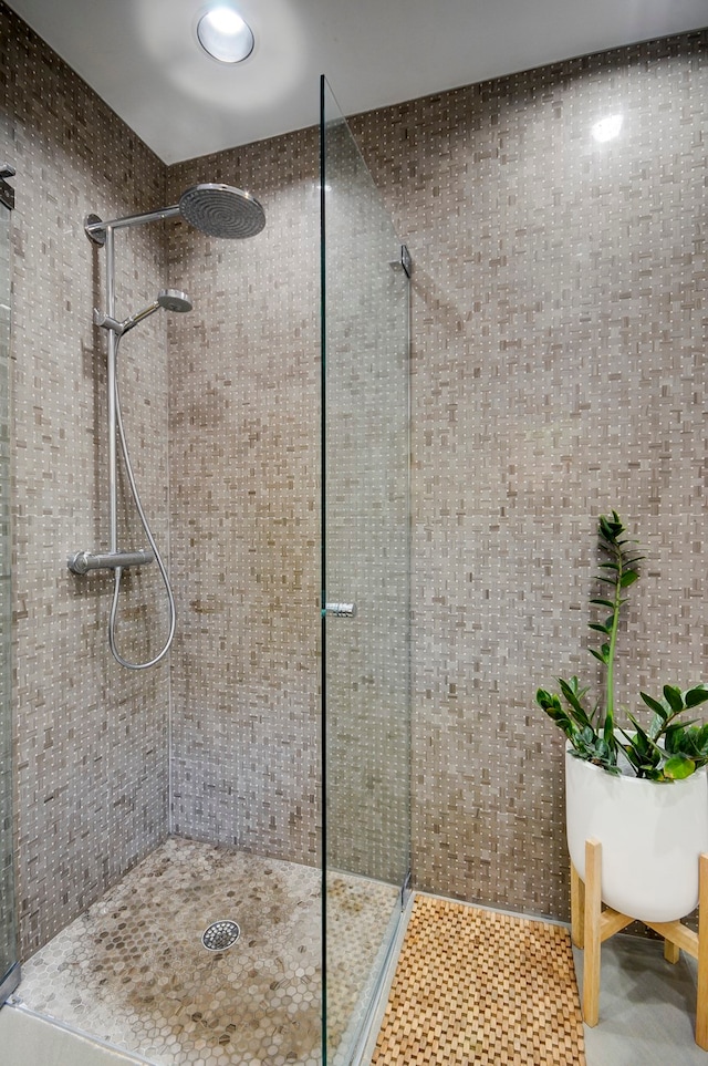 bathroom with tile walls, tile patterned flooring, and a tile shower