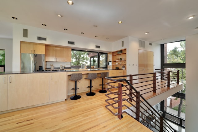 kitchen featuring light brown cabinetry, a wealth of natural light, stainless steel refrigerator, and light hardwood / wood-style floors