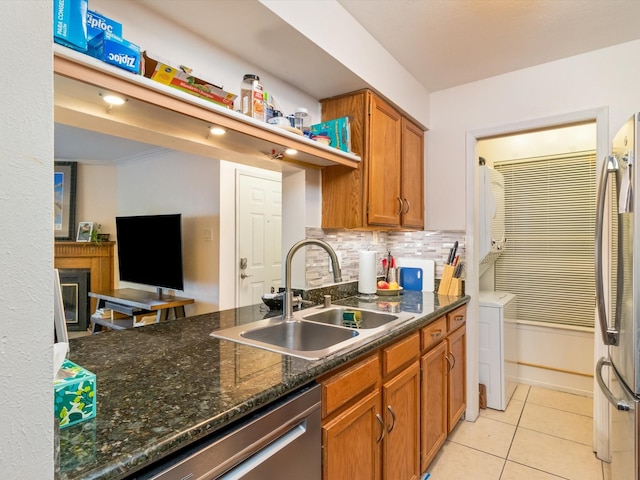 kitchen featuring brown cabinets, a sink, backsplash, appliances with stainless steel finishes, and light tile patterned flooring