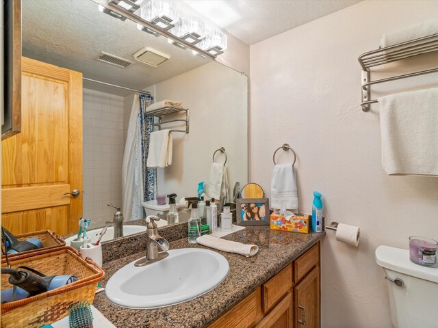 full bath with visible vents, toilet, vanity, a shower with curtain, and a textured ceiling