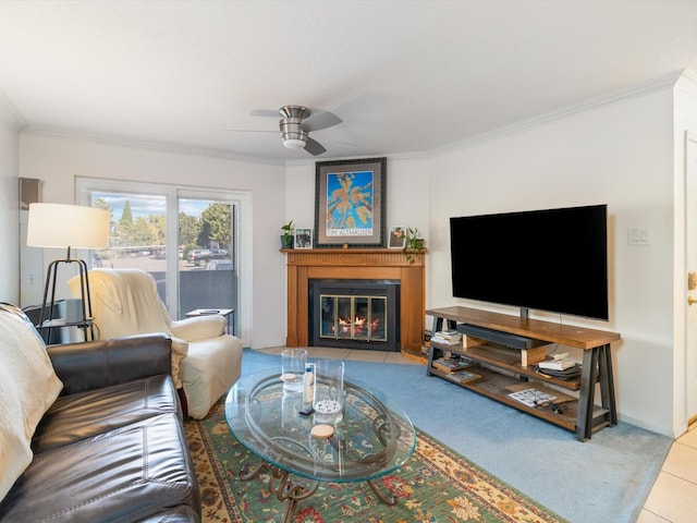 living room featuring tile patterned floors, a fireplace with flush hearth, a ceiling fan, crown molding, and baseboards