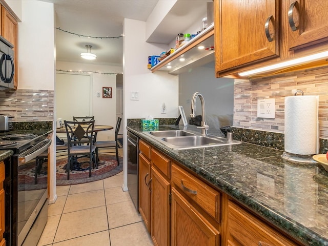 kitchen featuring tasteful backsplash, light tile patterned floors, appliances with stainless steel finishes, brown cabinetry, and a sink