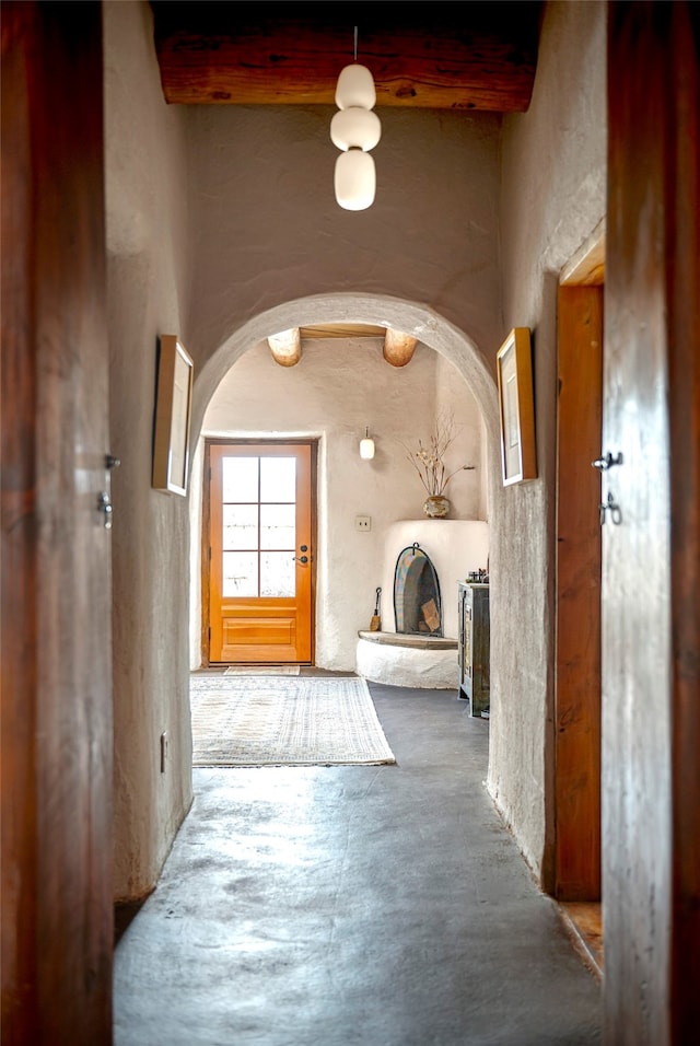 hallway featuring beamed ceiling and concrete floors