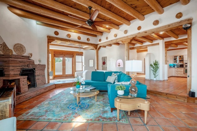 living room with a fireplace, ceiling fan, beam ceiling, and french doors