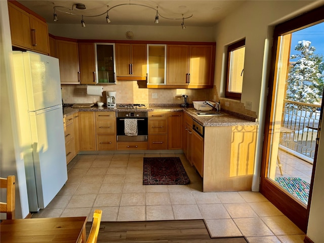 kitchen featuring light tile patterned flooring, stainless steel appliances, stone counters, decorative backsplash, and sink