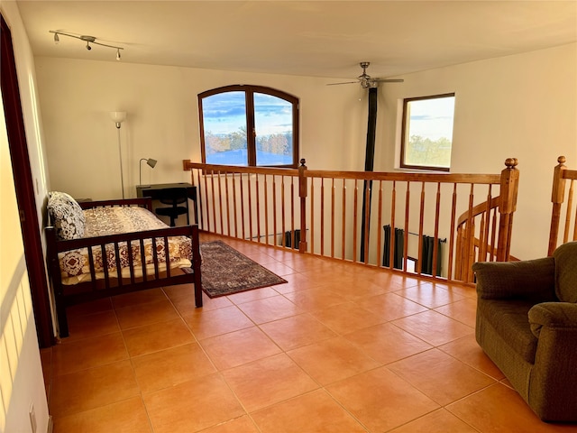 tiled bedroom featuring ceiling fan and multiple windows