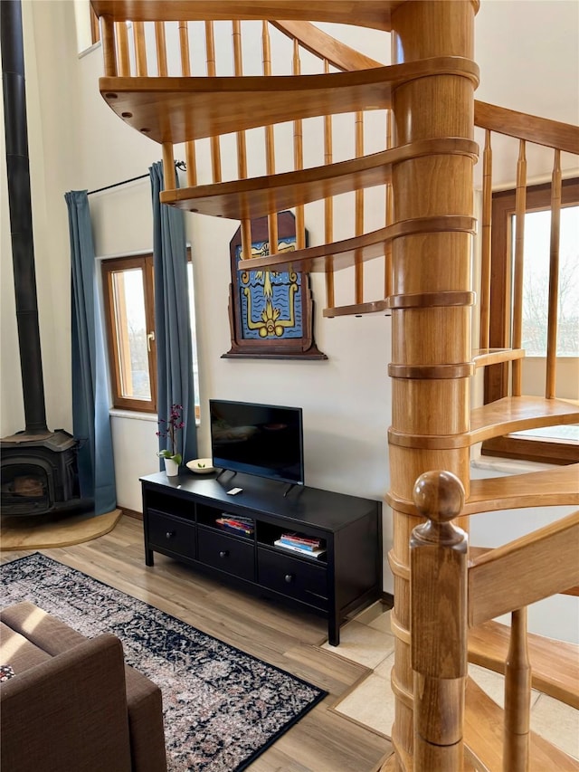 living room featuring light wood-style flooring, stairway, a healthy amount of sunlight, and a wood stove