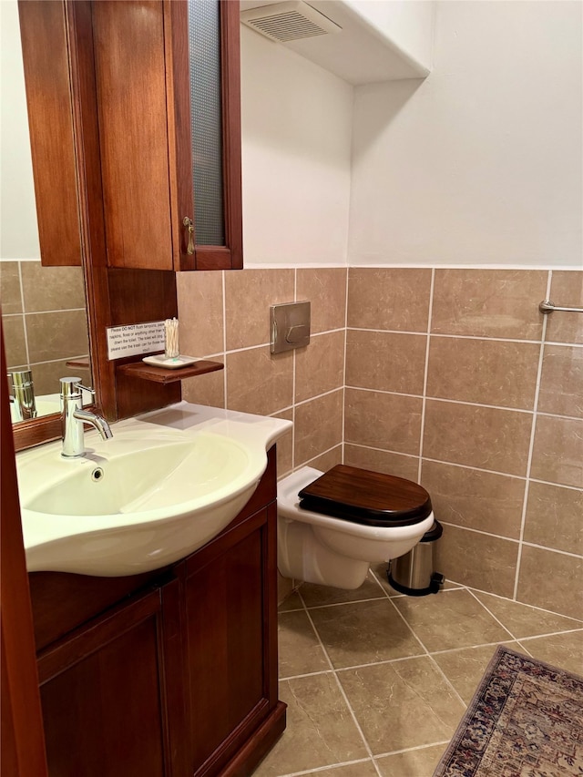 bathroom featuring tile patterned flooring, vanity, toilet, and tile walls