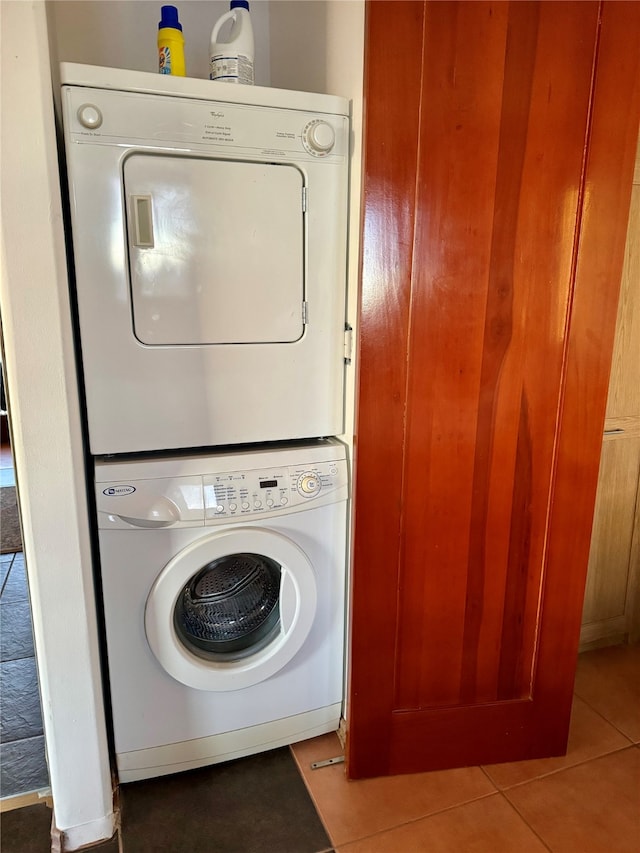 laundry area with stacked washer / drying machine and tile patterned floors