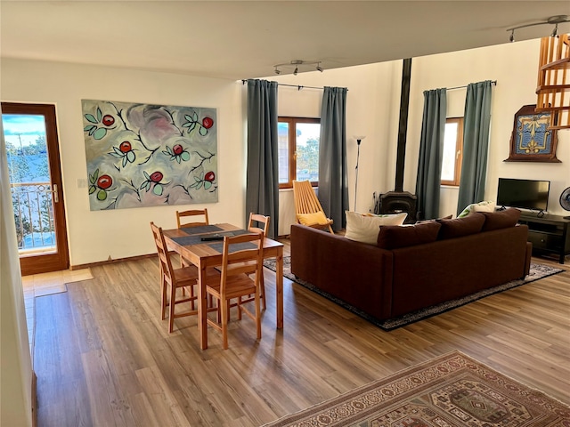 living room with a wood stove, light hardwood / wood-style flooring, and rail lighting