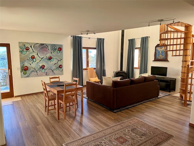 living room with track lighting, a wood stove, and wood finished floors