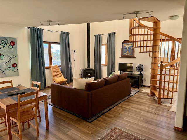 living room with a wood stove, track lighting, and wood-type flooring