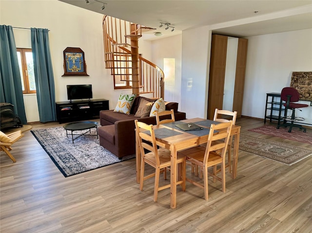 dining area with stairway, light wood-style floors, rail lighting, baseboards, and a wood stove