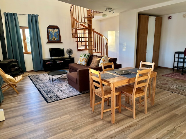 dining room with a wood stove, light hardwood / wood-style floors, and rail lighting