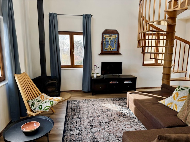 living room with stairs, a wood stove, and wood finished floors