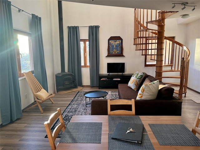 living area featuring stairs, a wood stove, plenty of natural light, and wood finished floors