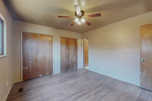2709 Paseo De Tularosa, Santa Fe, NM 87505 - unfurnished bedroom featuring ceiling fan, a textured ceiling, light hardwood / wood-style flooring, and two closets