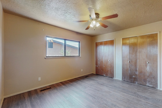 2709 Paseo De Tularosa, Santa Fe, NM 87505 - unfurnished bedroom featuring ceiling fan, wood-type flooring, a textured ceiling, and two closets