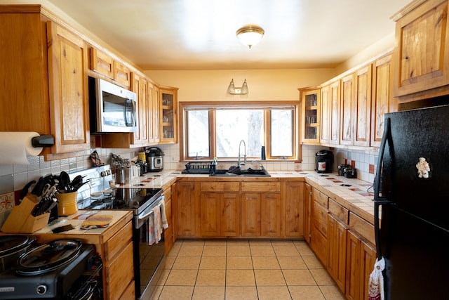 kitchen featuring tile counters, sink, black appliances, and decorative backsplash