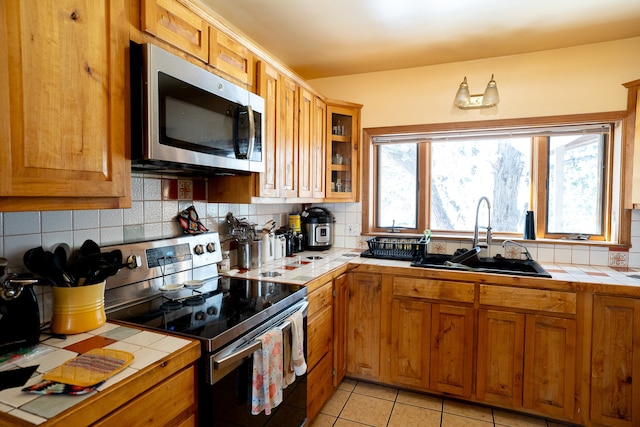 kitchen featuring stainless steel appliances, tile countertops, light tile patterned floors, and sink