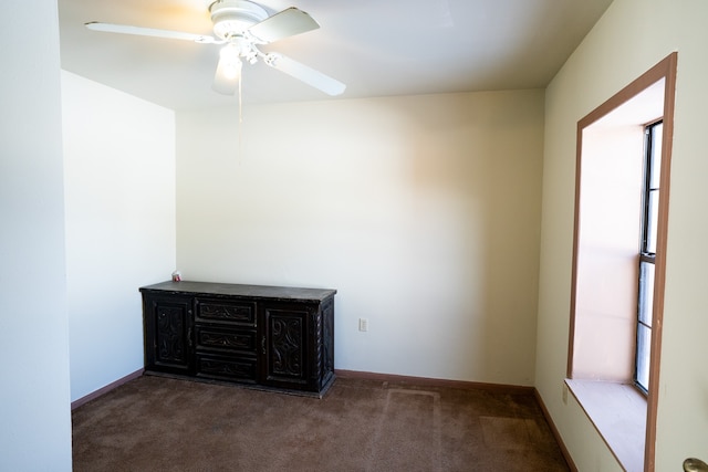 spare room featuring dark colored carpet and ceiling fan