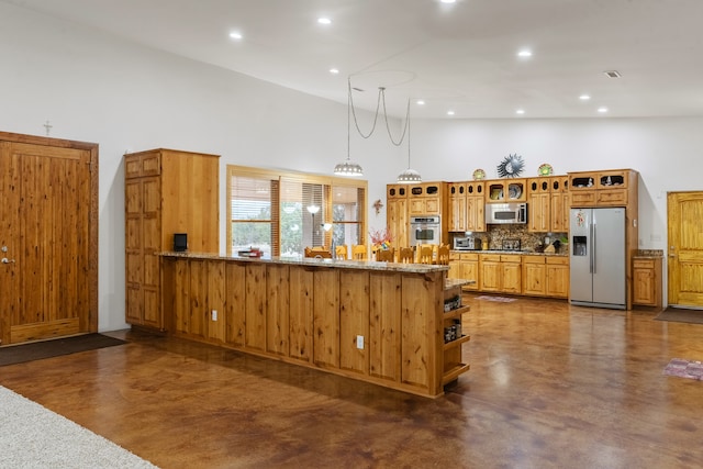 kitchen with kitchen peninsula, appliances with stainless steel finishes, decorative light fixtures, and light stone countertops