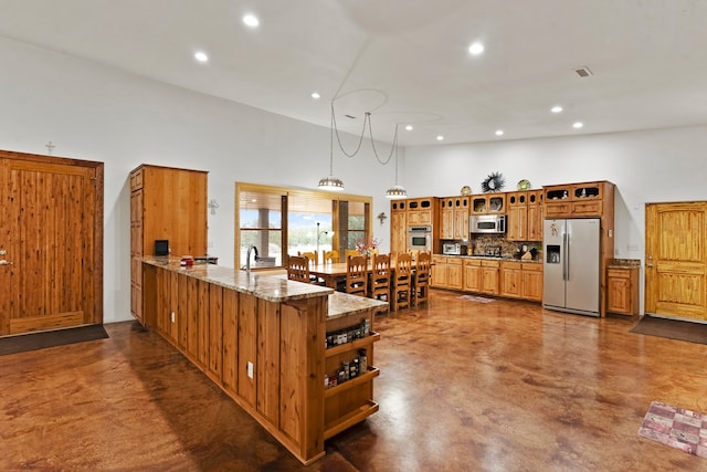 kitchen with stainless steel appliances, light stone counters, kitchen peninsula, tasteful backsplash, and hanging light fixtures