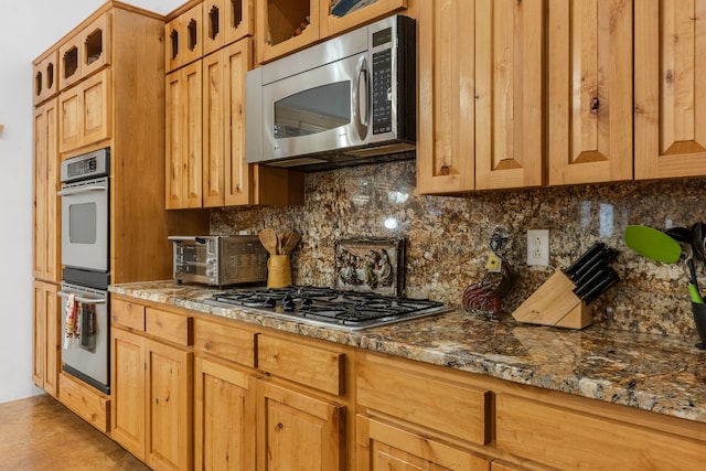 kitchen featuring tasteful backsplash, appliances with stainless steel finishes, and stone countertops