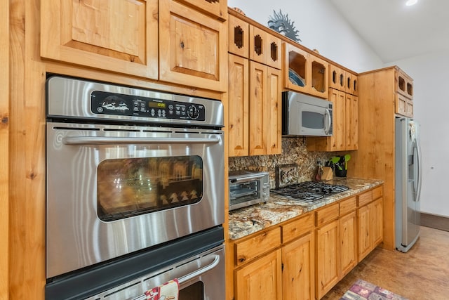 kitchen with stainless steel appliances, light carpet, light stone counters, backsplash, and lofted ceiling