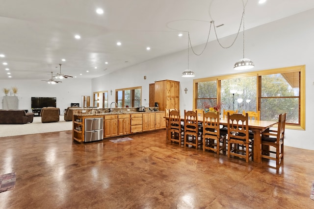 dining area featuring concrete flooring, ceiling fan, sink, and vaulted ceiling