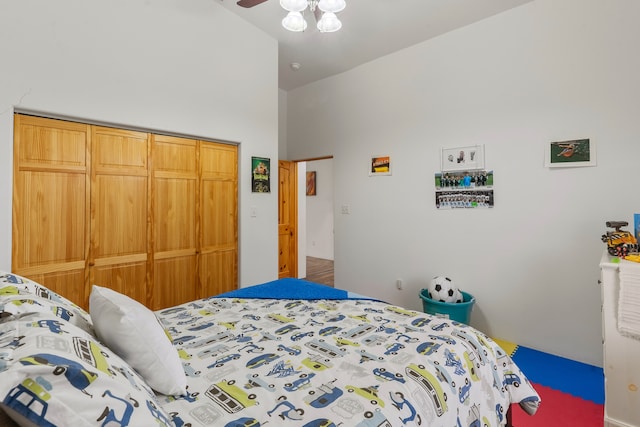 carpeted bedroom with high vaulted ceiling, ceiling fan, and a closet