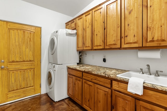 laundry area featuring stacked washer and dryer, cabinets, and sink