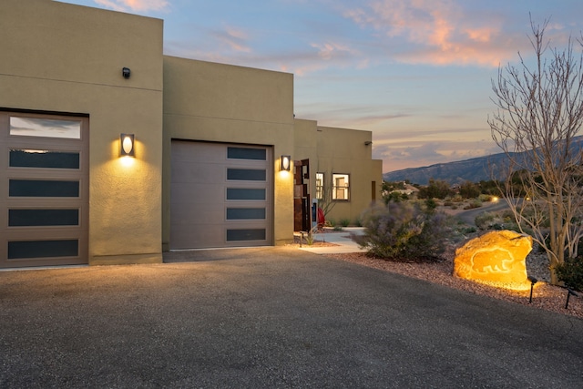 exterior entry at dusk with a mountain view and a garage