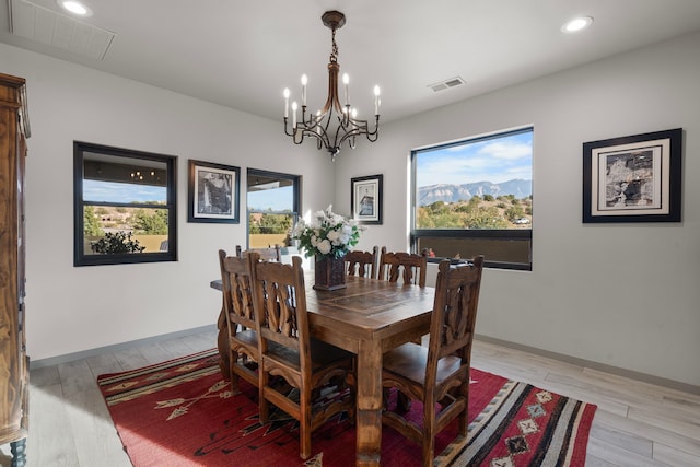 dining area featuring light hardwood / wood-style floors, a healthy amount of sunlight, and an inviting chandelier