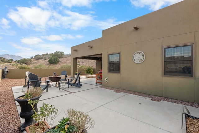 view of patio with a mountain view and an outdoor fire pit