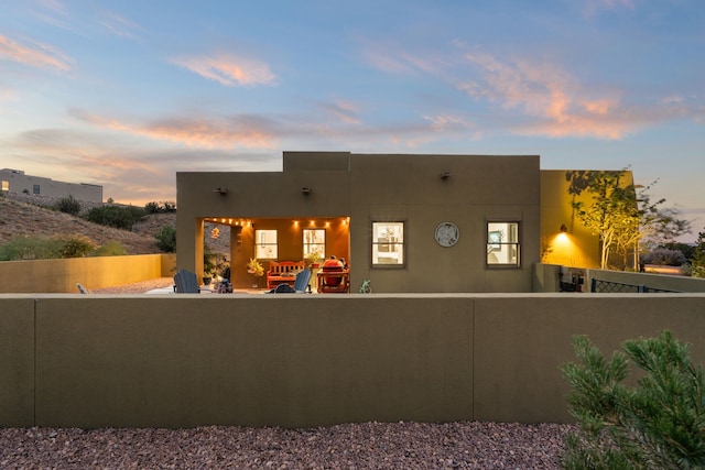 back house at dusk featuring a patio