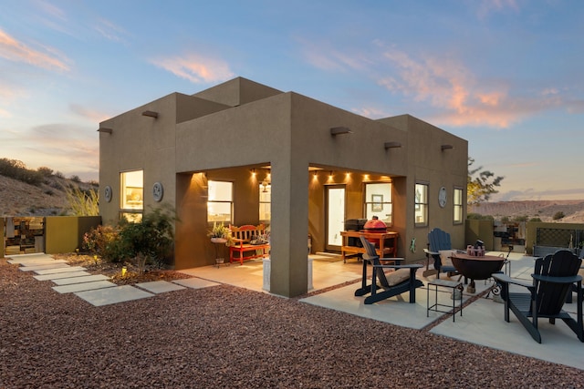 back house at dusk with a patio area