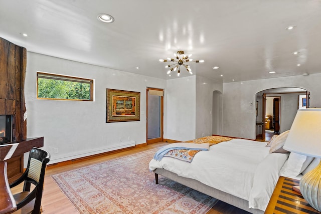 bedroom featuring arched walkways, a notable chandelier, a baseboard heating unit, recessed lighting, and light wood-style floors